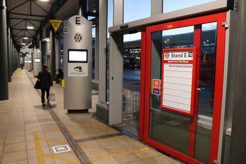Wolverhampton Bus Station: NaviLens codes on the floor, on the Stand E column and on the departures sign, with a traveler walking along the concourse