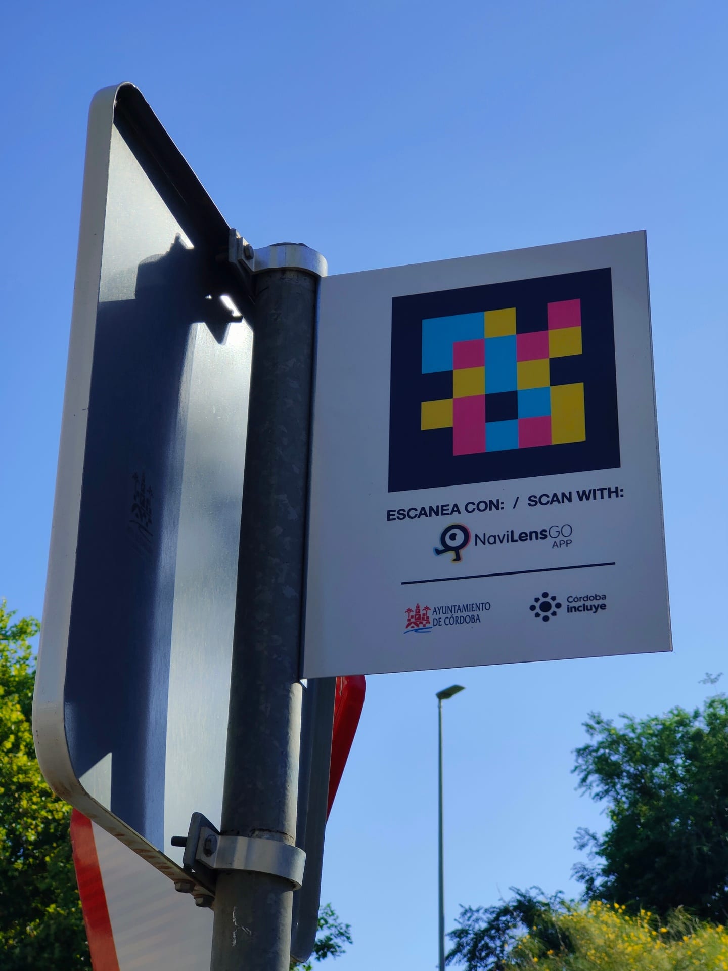 Schild „Scan mit NaviLens GO · Stadt Córdoba · Córdoba Incluye“ am Pfosten eines Taxi-Stands an der Avenida Aeropuerto in Córdoba