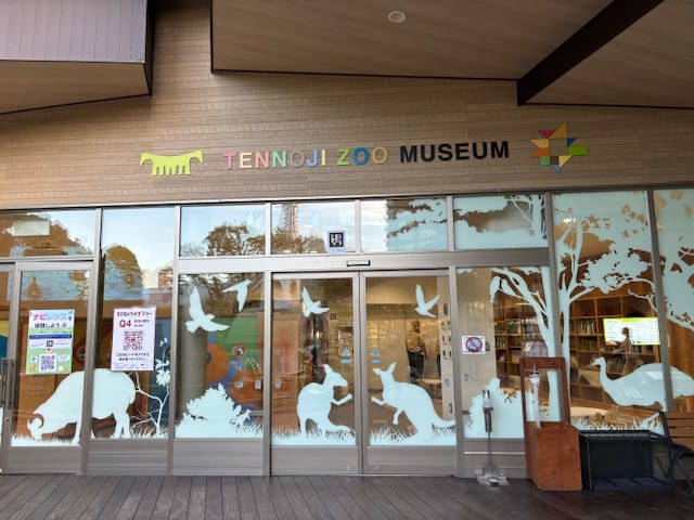 Façade of the TENNOJI ZOO MUSEUM in Osaka, stained-glass windows with animal silhouettes and NaviLens posters on the door