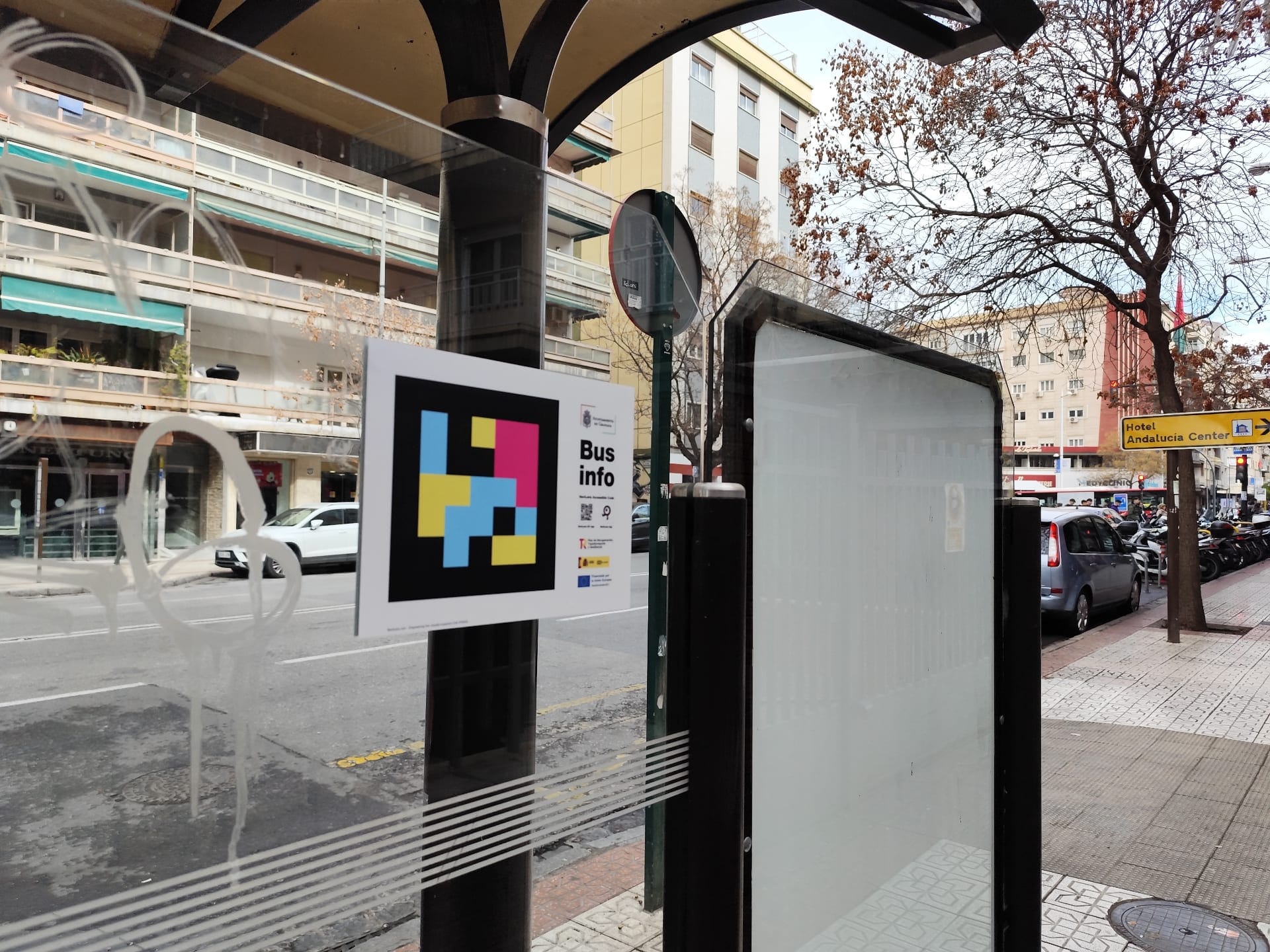 Marquesina de bus en Camino de Ronda (Granada) con un cartel «Bus info — NaviLens Accessible Code» del Ayuntamiento de Granada y el sello NextGenerationEU
