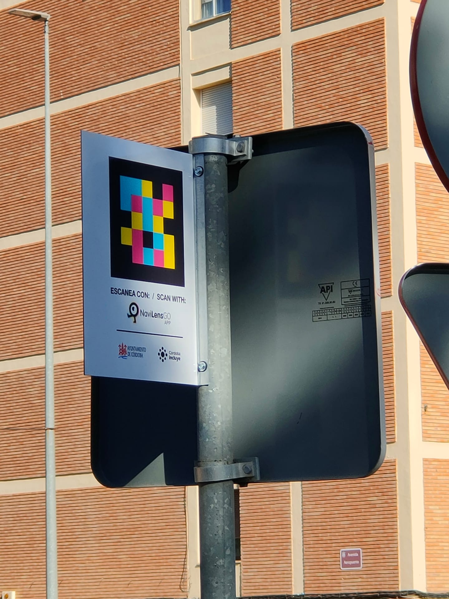 Schild „Scan mit NaviLens GO · Stadt Córdoba · Córdoba Incluye“ am Pfosten eines Taxi-Stands an der Avenida Aeropuerto in Córdoba