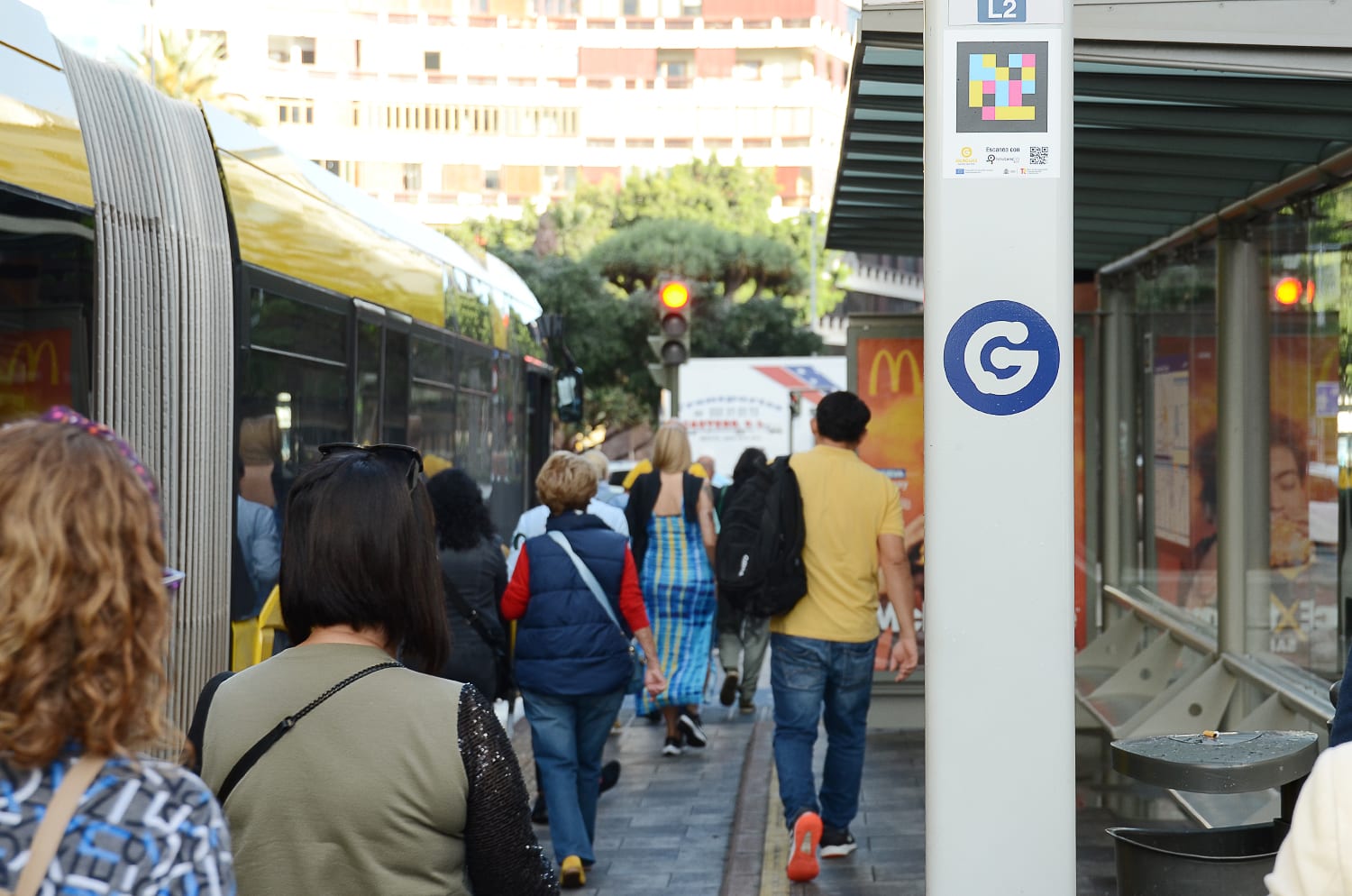 Abribus de l'arrêt L2 de Guaguas Municipales à Las Palmas de Gran Canaria avec le code NaviLens et la guagua jaune qui approche