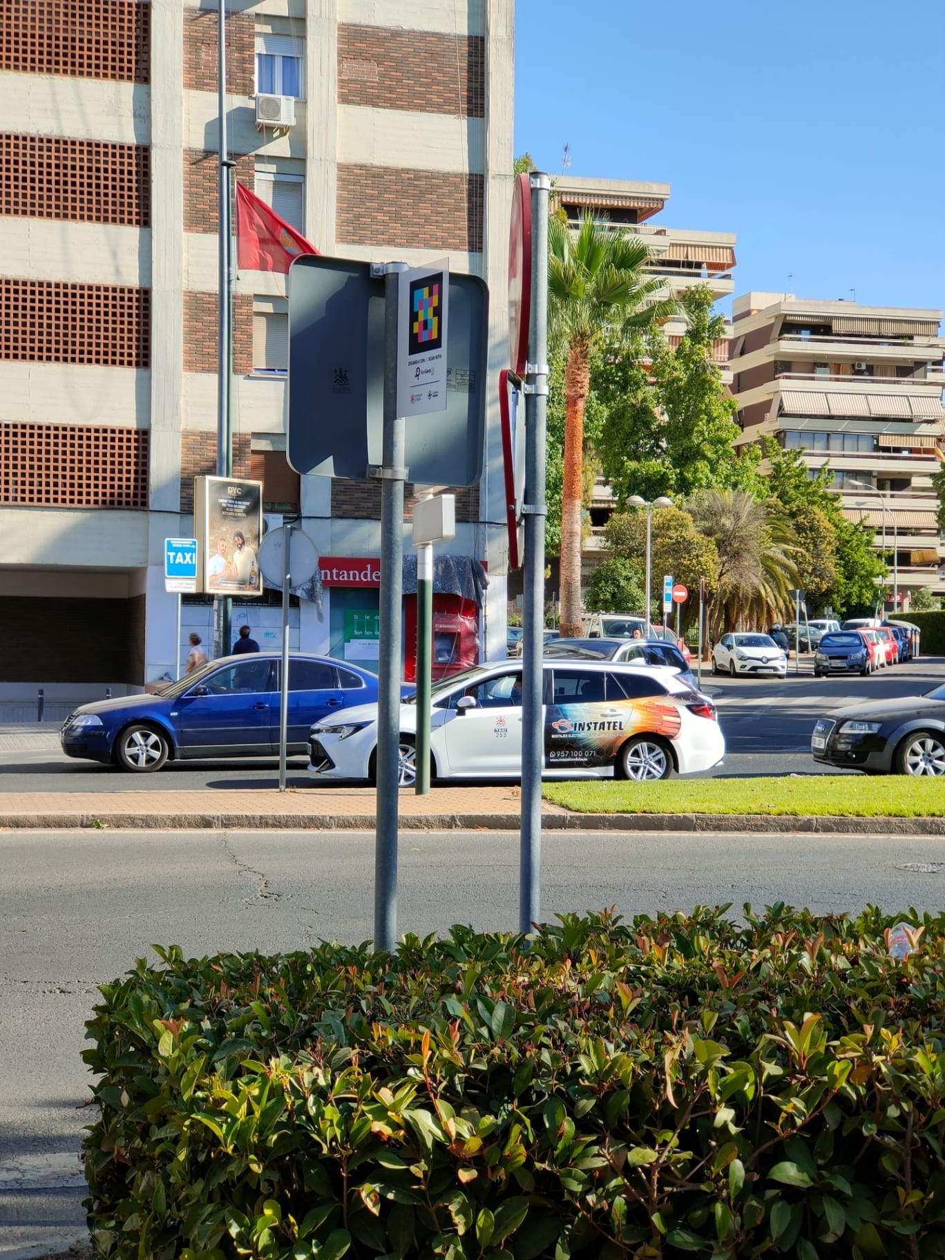 Parada de taxi en una rotonda de Córdoba con cartel NaviLens y un taxi blanco al fondo