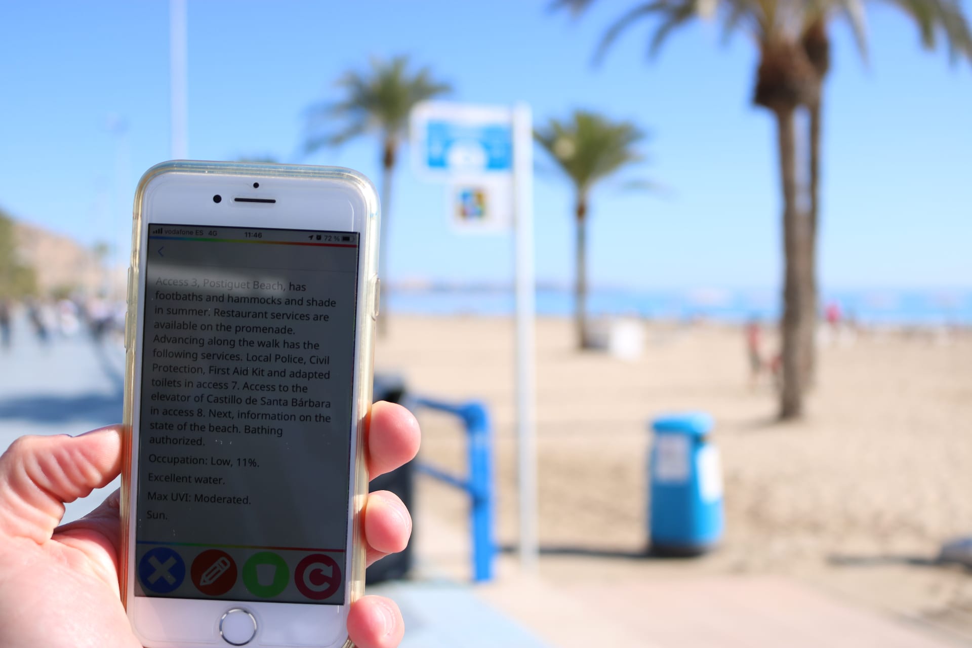 Phone reading a NaviLens code at access point 3 of Postiguet Beach showing English information on services, occupancy, water and UV index