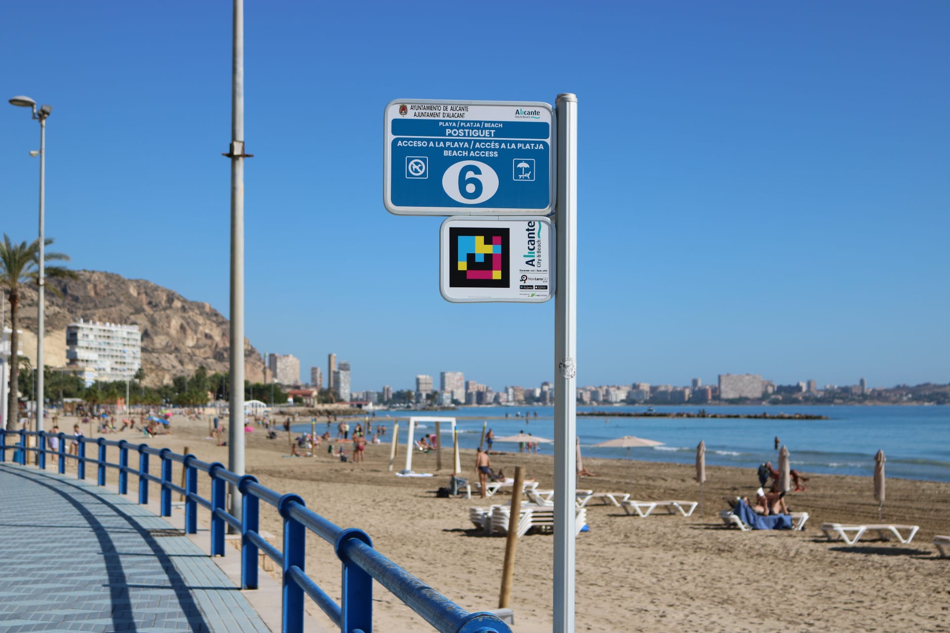 Information post at access point 6 of Postiguet Beach (Alicante) with the Alicante City Council NaviLens code and the city in the background